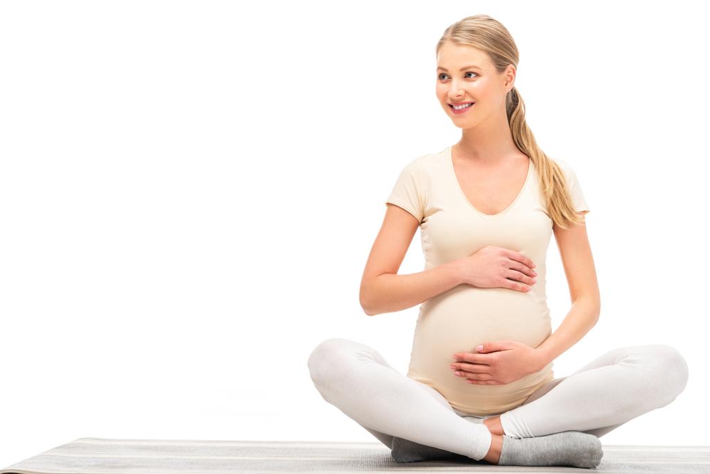 mujer embarazada sentada en pose de loto y mirando hacia otro lado aislada en blanco
 - Foto, imagen
