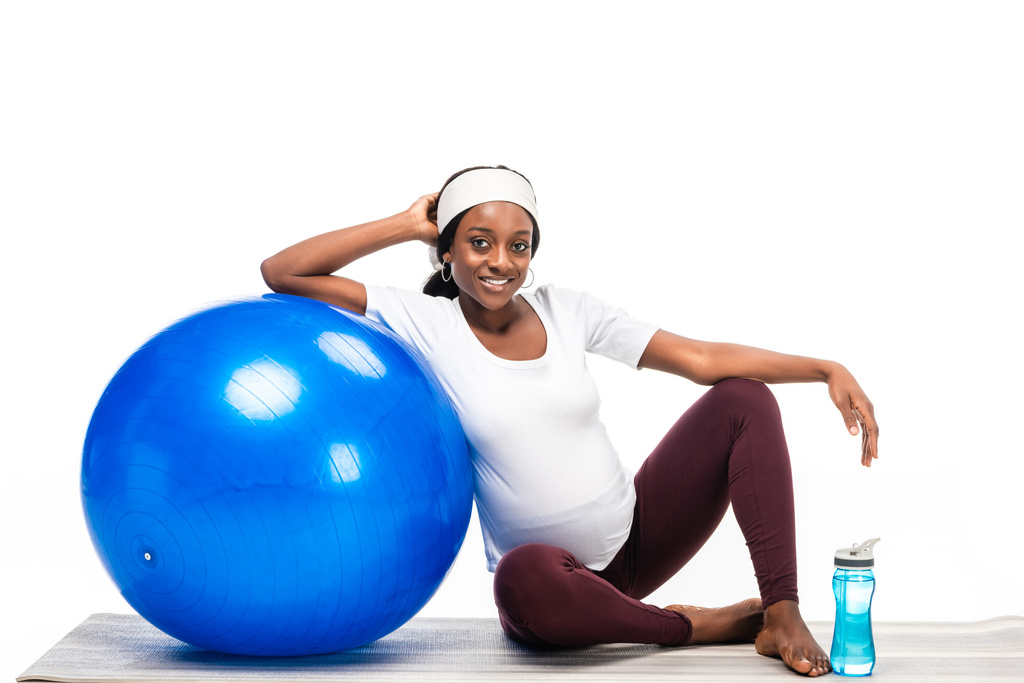 donna afroamericana seduta sul pavimento con palla fitness isolata su bianco
 - Foto, immagini