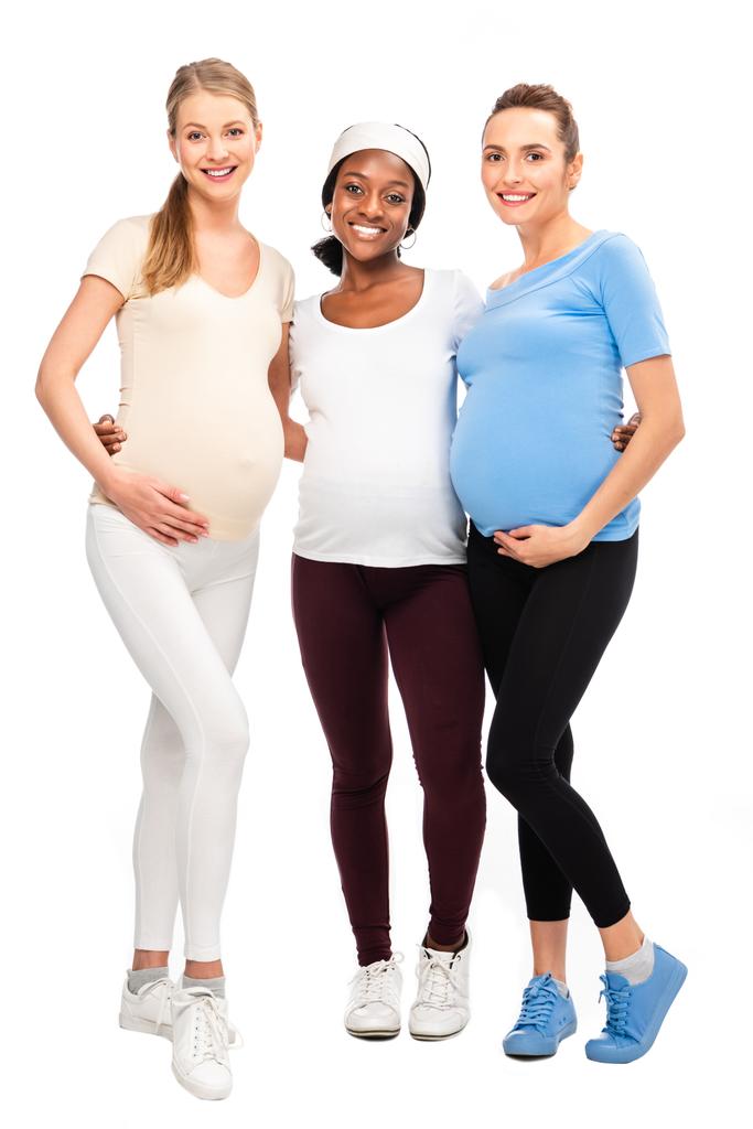comprimento total de três mulheres grávidas de pé e abraçando isolado no branco
 - Foto, Imagem