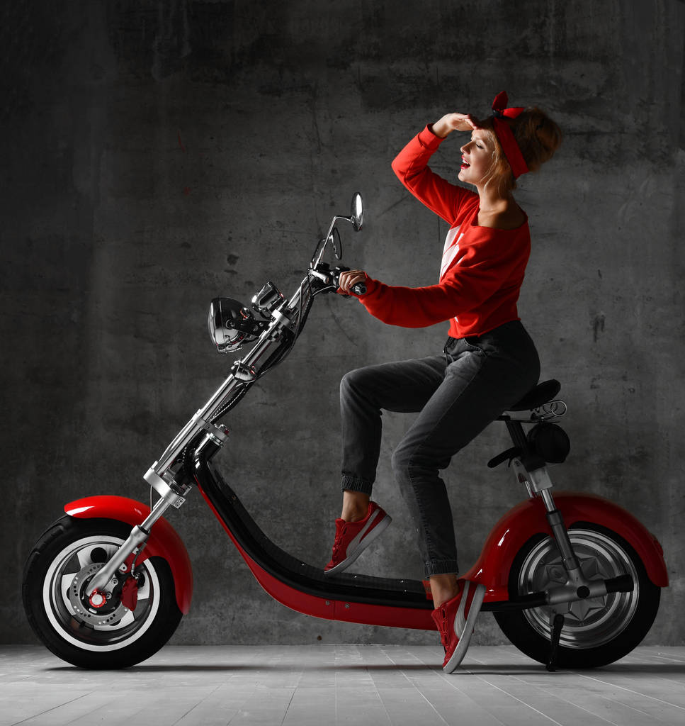 Женщина едет сидеть на мотоцикле скутер пинап ретро стиле смеясь улыбаясь глядя на угол
 - Фото, изображение