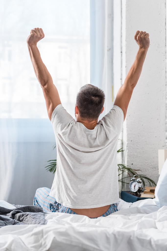 back view of man stretching in morning in bedroom - Photo, Image