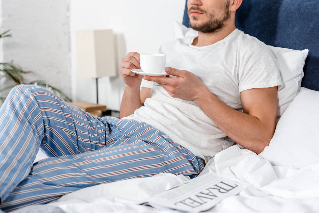 περικομμένη εικόνα του ανθρώπου που κρατώντας το φλιτζάνι του καφέ πρωί στο υπνοδωμάτιο - Φωτογραφία, εικόνα