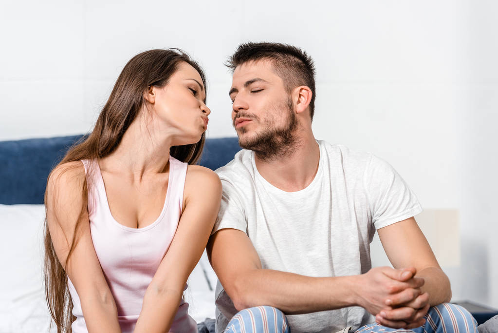 tyttöystävä ja poikaystävä pyjamassa menossa suudella sängyssä makuuhuoneessa
 - Valokuva, kuva