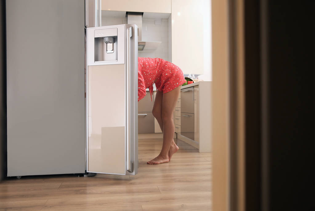 Молода жінка вибирає їжу в холодильнику вдома
 - Фото, зображення