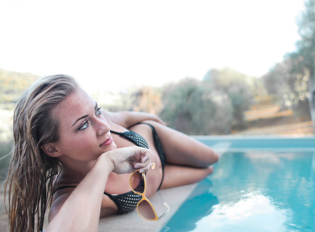 Красива молода жінка лежить біля басейну
  - Фото, зображення