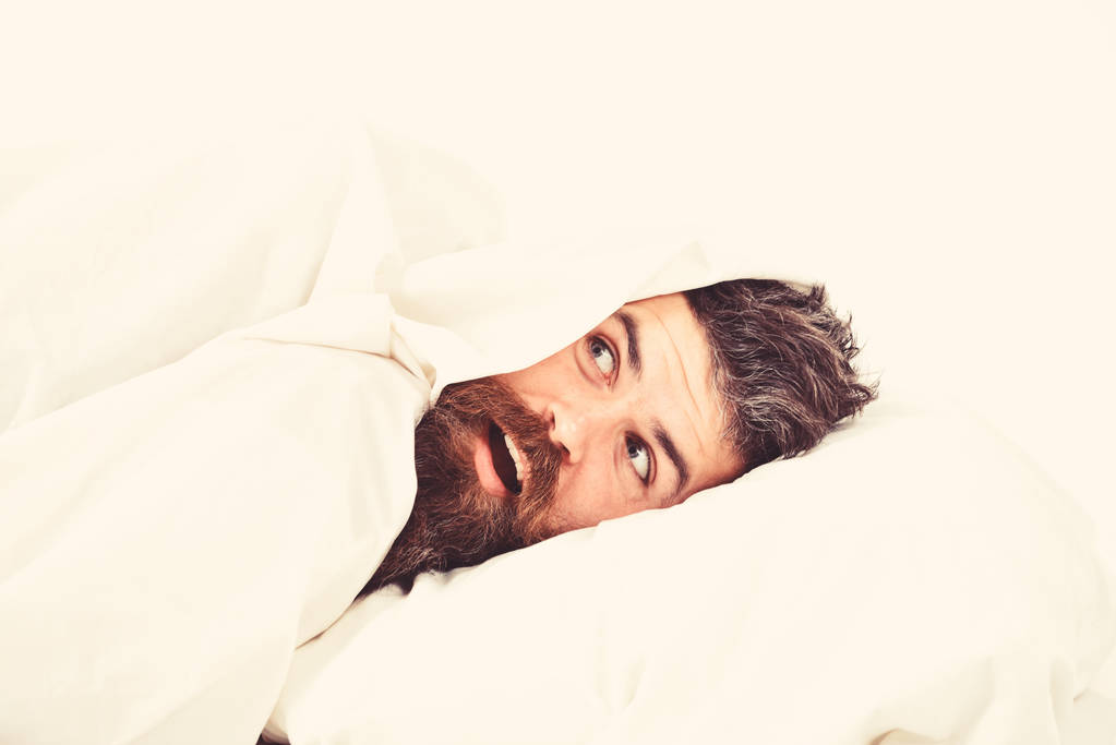 Hombre con barba y bigote escondido en la cama en blanco
 - Foto, Imagen