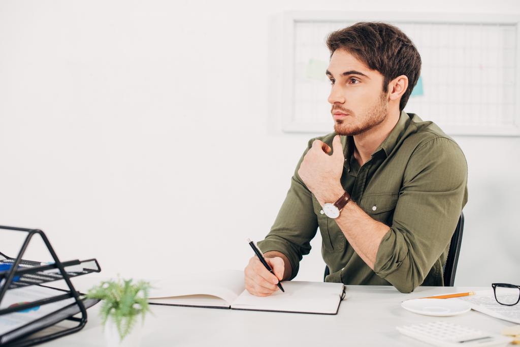 Бизнесмен сидит за столом и думает с ручкой в руке
 - Фото, изображение