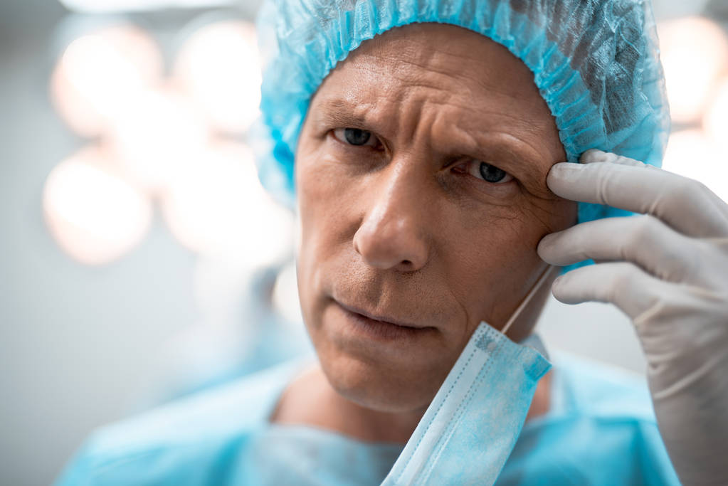 Κοντινό πλάνο καταπονημένος γιατρός frowning και αγγίζοντας το μέτωπό του - Φωτογραφία, εικόνα