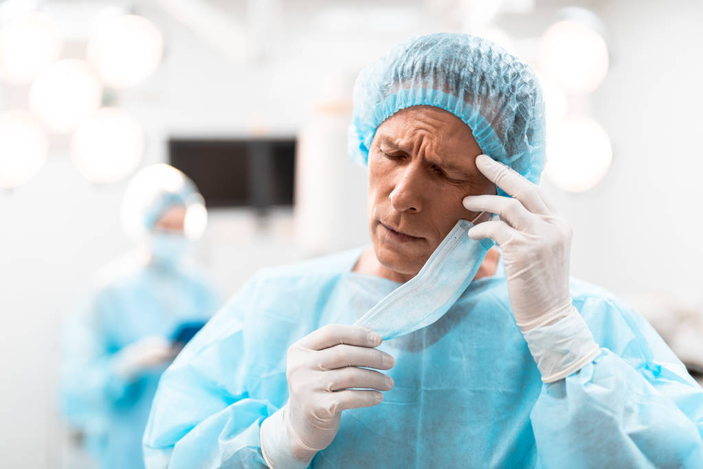 Fáradt orvos megérintette a fejét, miközben áll a szeme zárva - Fotó, kép