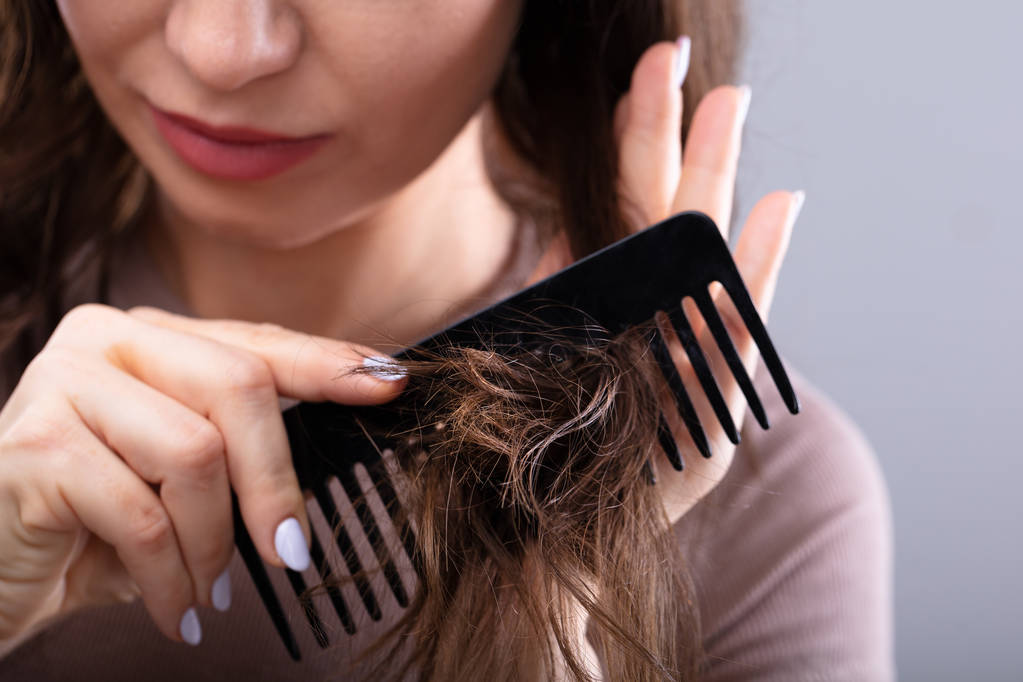 Primer plano de la mano de una mujer peinándose el pelo con peine
 - Foto, imagen