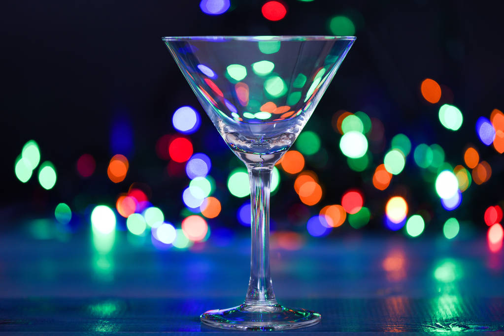 Cocktail glass on defocused garland colorful lights. What to drink on christmas party. Alcohol cocktail for winter party. Cocktail ideas concept. Easy recipes for winter alcoholic cocktail drinks - Photo, Image