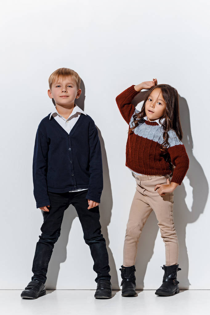 das Porträt von niedlichen kleinen Jungen und Mädchen in stylischer Jeanskleidung, die im Studio in die Kamera schauen - Foto, Bild