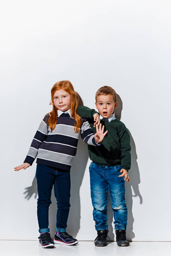 Le portrait de mignon petit garçon et fille en jeans élégants vêtements regardant la caméra au studio
 - Photo, image