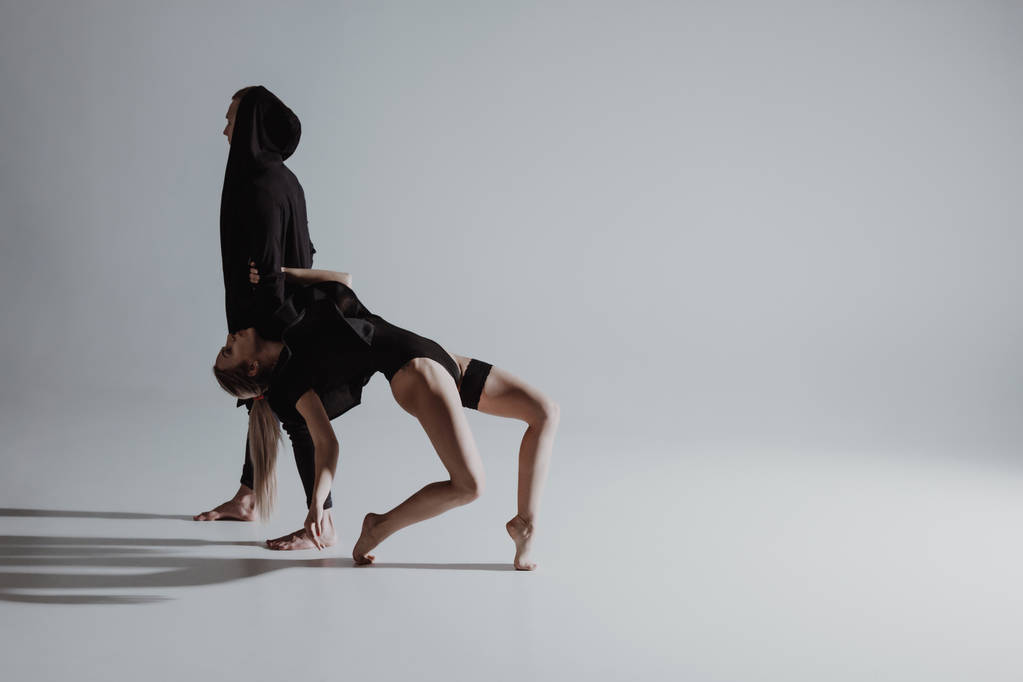 Δύο νέοι σύγχρονου μπαλέτου χορευτές παρουσιάζουν πάνω από γκρίζο φόντο στούντιο - Φωτογραφία, εικόνα