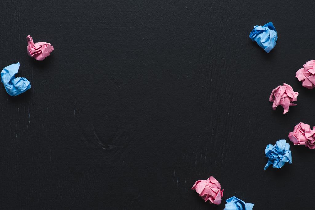 vue du dessus de boules de papier froissées dispersées roses et bleues sur fond noir, penser concept différent
 - Photo, image