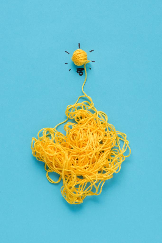 top view of light bulb sign made of yellow yarn on blue background, ideas concept - Photo, Image