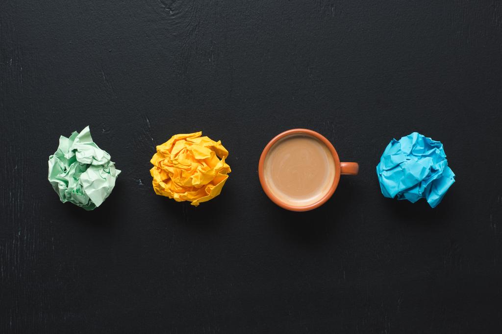 top view of colorful crumpled paper balls with coffee cup on black background - Photo, Image