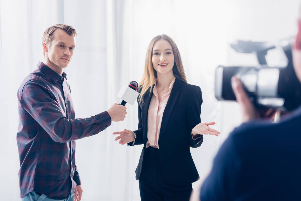 красивая деловая женщина в костюме дает интервью журналисту и жестом в офисе
 - Фото, изображение