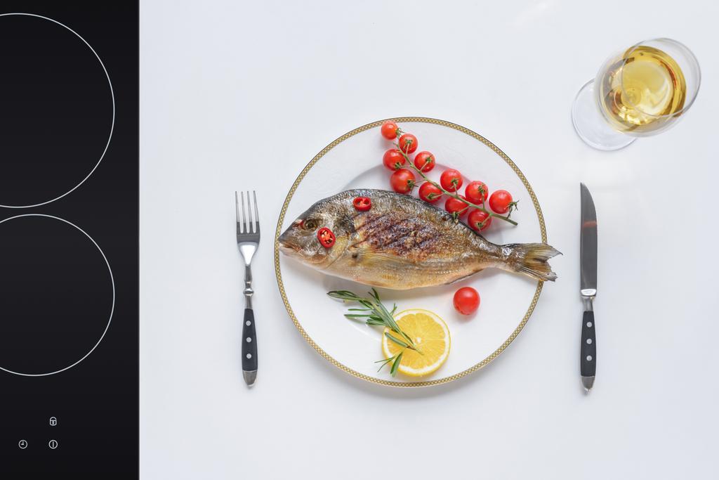 vista superior de delicioso pescado frito con tomates cherry, limón y romero en el plato
 - Foto, imagen