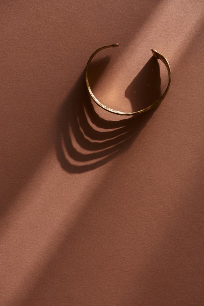 vista superior de hermosa pulsera de lujo en superficie marrón con luz solar
 - Foto, imagen