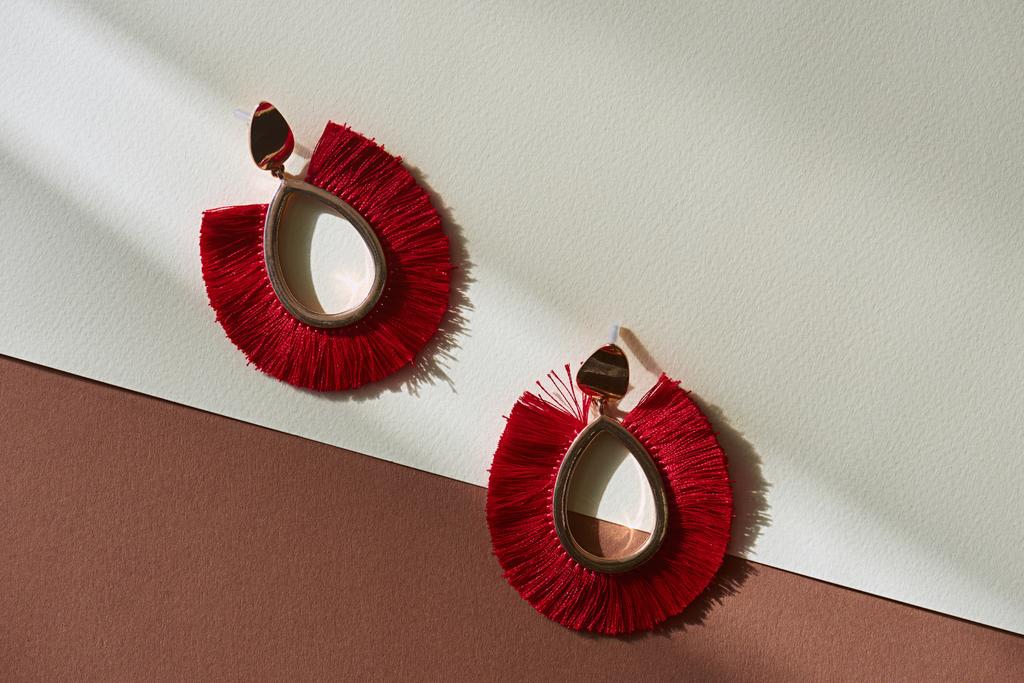 bovenaanzicht van mooie luxe rode oorbellen van bruine en witte ondergrond met zonlicht - Foto, afbeelding