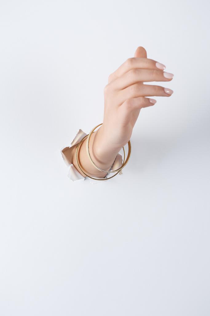 recortado de imagen mujer de la mano con hermosas pulseras a través de papel blanco
 - Foto, imagen