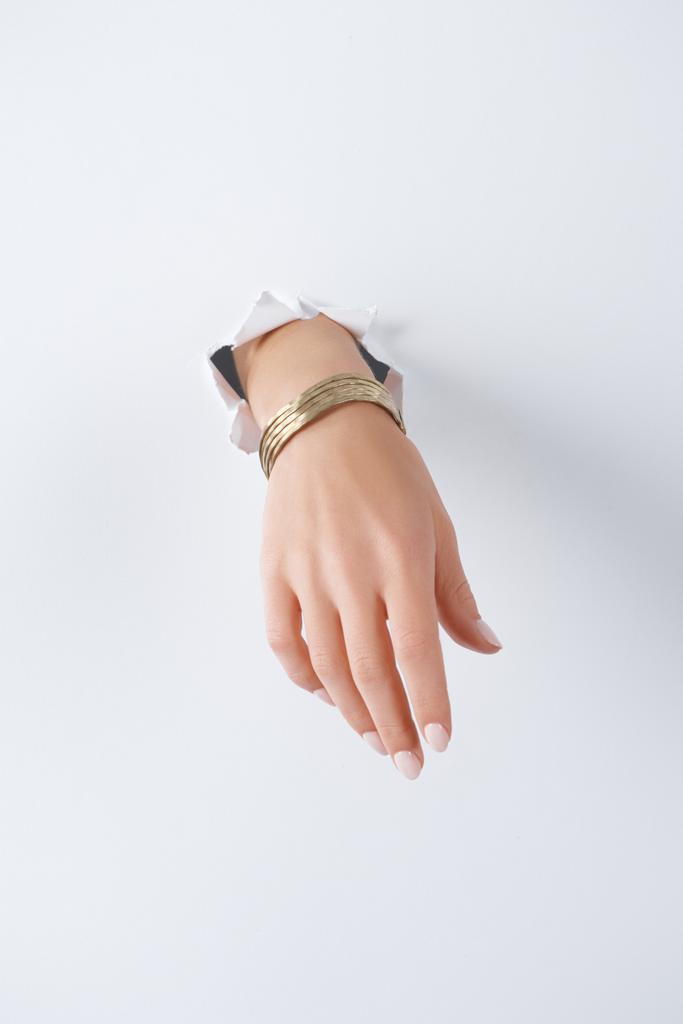 cropped image of woman holding hand with beautiful golden bracelet through white paper - Photo, Image