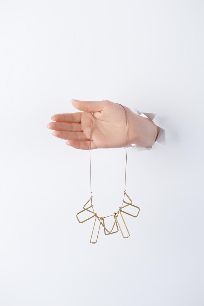 image recadrée de femme tenant la main avec un beau collier doré à travers du papier blanc
 - Photo, image