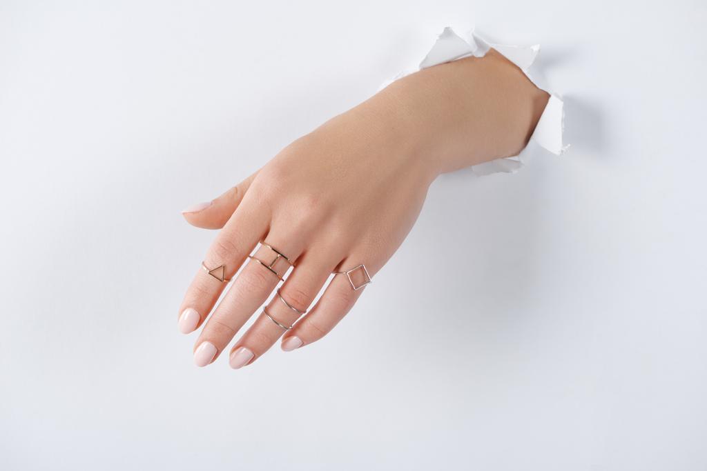 imagen recortada de mujer cogida de la mano con hermosos anillos de plata de lujo a través de papel blanco
 - Foto, Imagen