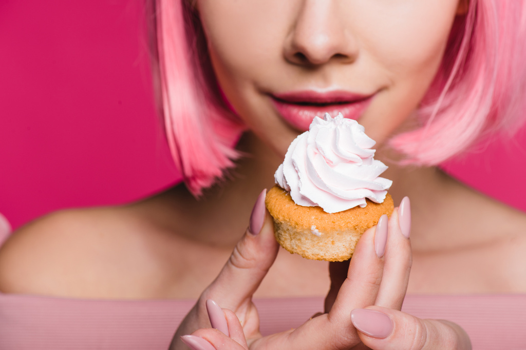 bijgesneden weergave van sensuele meisje houdt van zoete cupcake geïsoleerd op roze - Foto, afbeelding