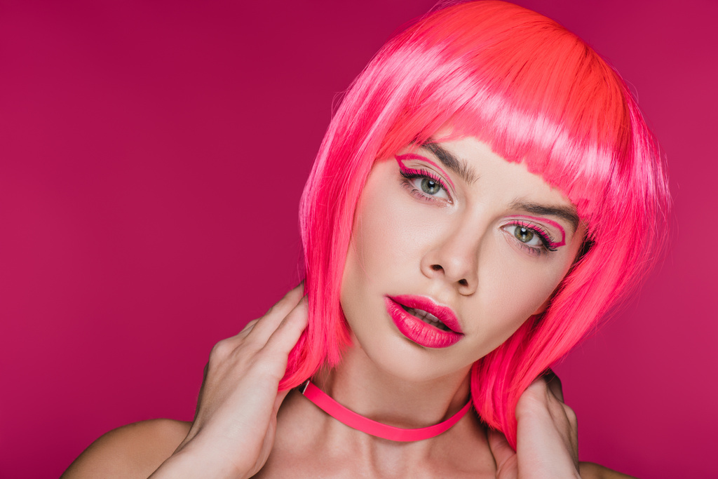 glamor model with fashionable makeup posing in neon pink wig, isolated on pink - Photo, Image