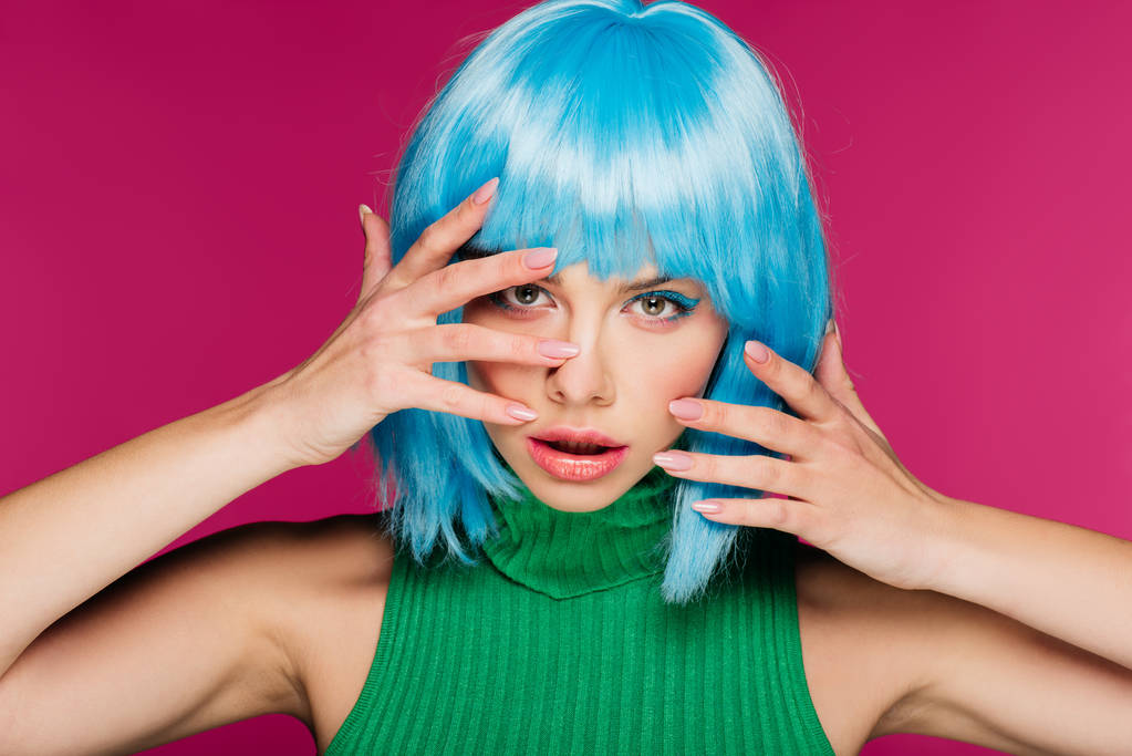 όμορφη νεαρή γυναίκα χειρονομίες και θέτοντας σε μπλε περούκα, απομονώνονται σε ροζ - Φωτογραφία, εικόνα