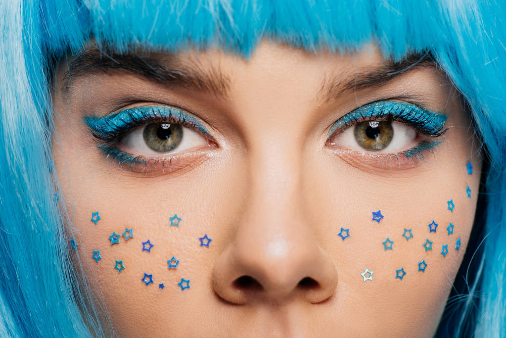 zblízka módní dívka s modrou parukou, make-up a hvězdy na tváři, izolované na fialová - Fotografie, Obrázek