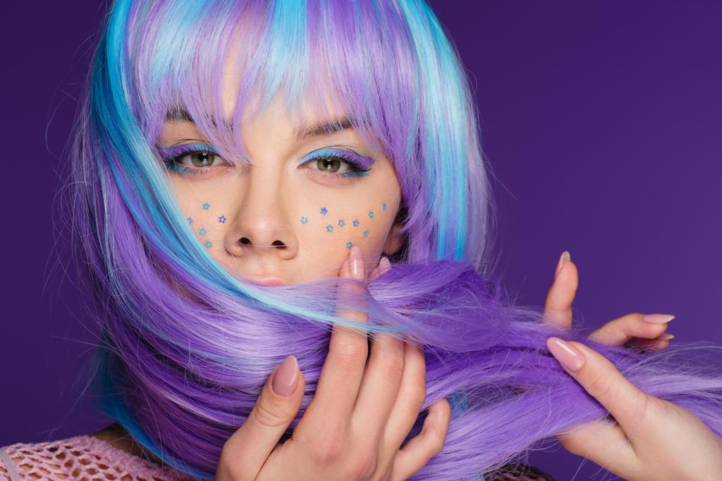 attractive sensual girl posing in violet wig with stars on face, isolated on purple - Photo, Image