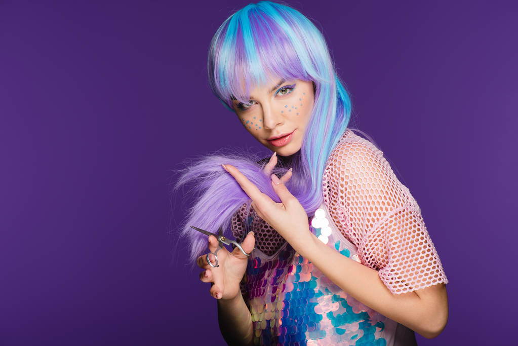 krásná dívka s hvězdami na tváři řezání fialové vlasy s nůžkami, izolované na fialová - Fotografie, Obrázek