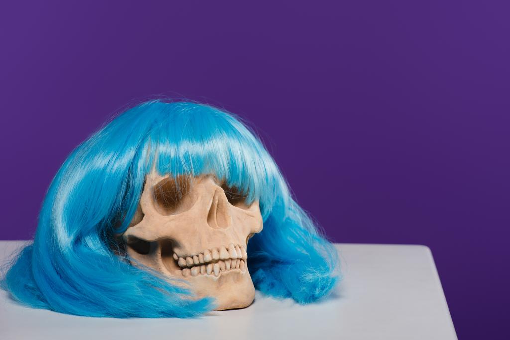skull in blue wig on purple background with copy space - Photo, Image