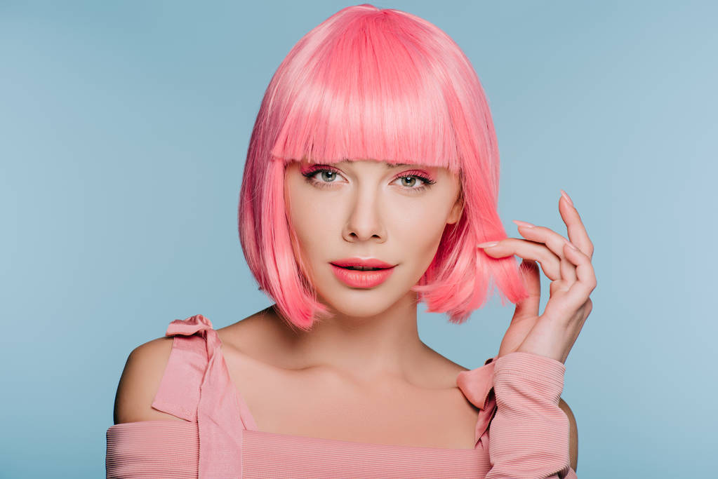 ελκυστική μοντέρνα γυναίκα χειρονομίες και θέτοντας σε ροζ περούκα που απομονώνονται σε μπλε - Φωτογραφία, εικόνα