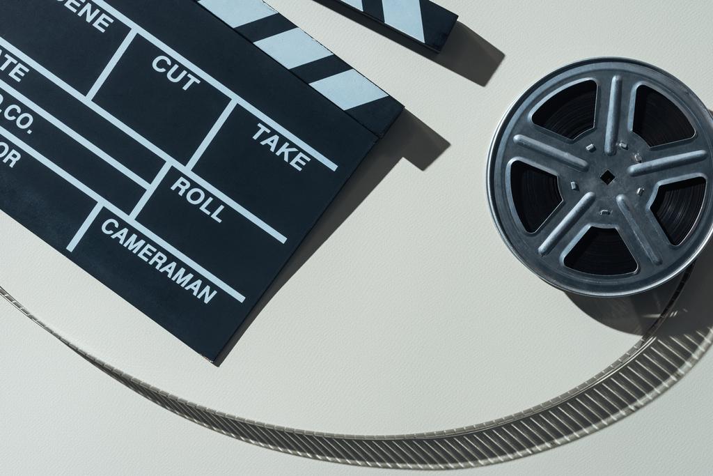 top view of clapperboard and film reel with cinema tape on grey background - Photo, Image