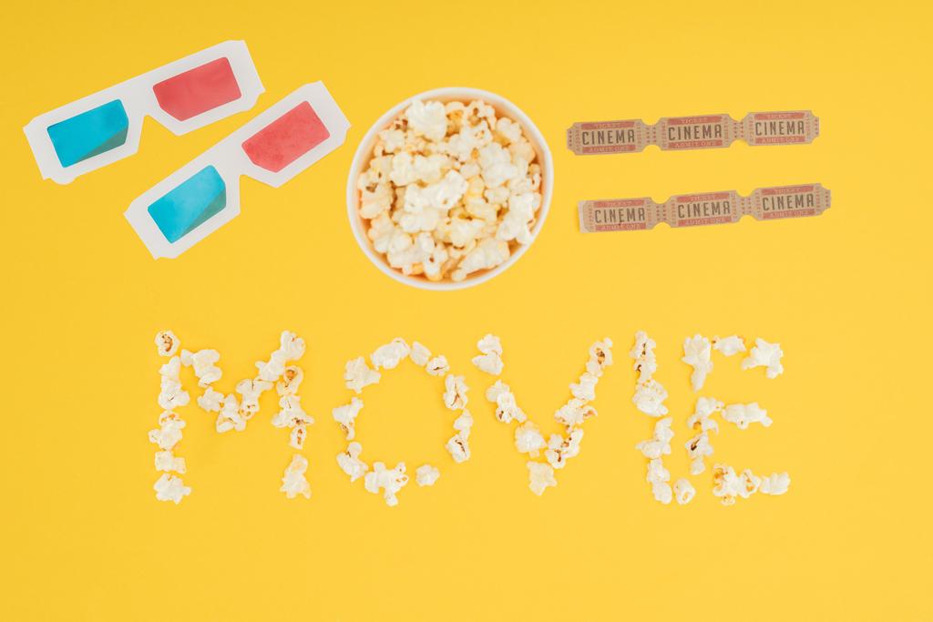 vista dall'alto di bicchieri 3d, secchio con popcorn, biglietti per il cinema e scritte "film" realizzate con popcorn isolati su giallo
 - Foto, immagini