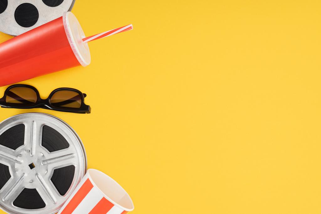 плівкові барабани, 3d окуляри, попкорн і червона одноразова чашка з соломою ізольовані на жовтому
 - Фото, зображення