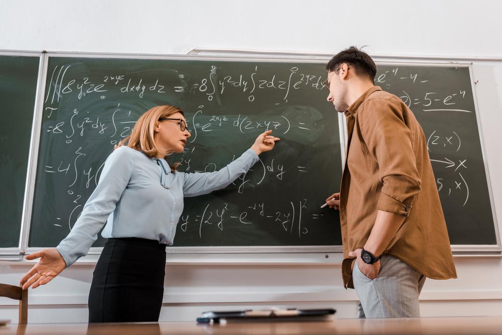 Θηλυκό καθηγητής δείχνοντας εξισώσεις μαθητή στην τάξη  - Φωτογραφία, εικόνα