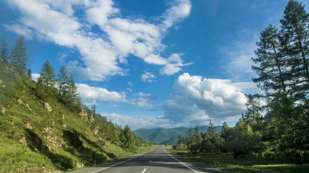 Hermosas vistas y paisaje de la naturaleza Altai. Perspectiva de la carretera y carretera en Altai, sobre el telón de fondo de majestuosas montañas cubiertas de bosque y cielo con nubes
. - Foto, imagen