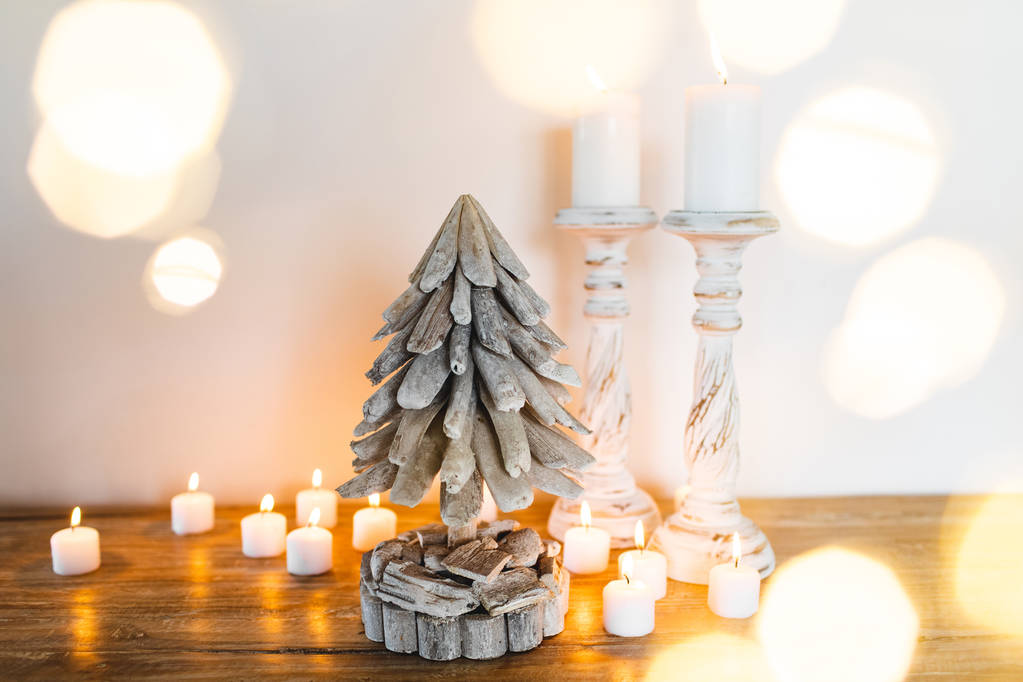 Árbol de Navidad decorado de madera blanca con velas y luces brillantes borrosas doradas alrededor. Lugar para texto. Concepto festivo hecho a mano
 - Foto, imagen