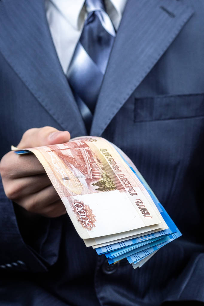 Un uomo tiene rubli e dollari in mano, un uomo d'affari tiene i soldi in mano
 - Foto, immagini