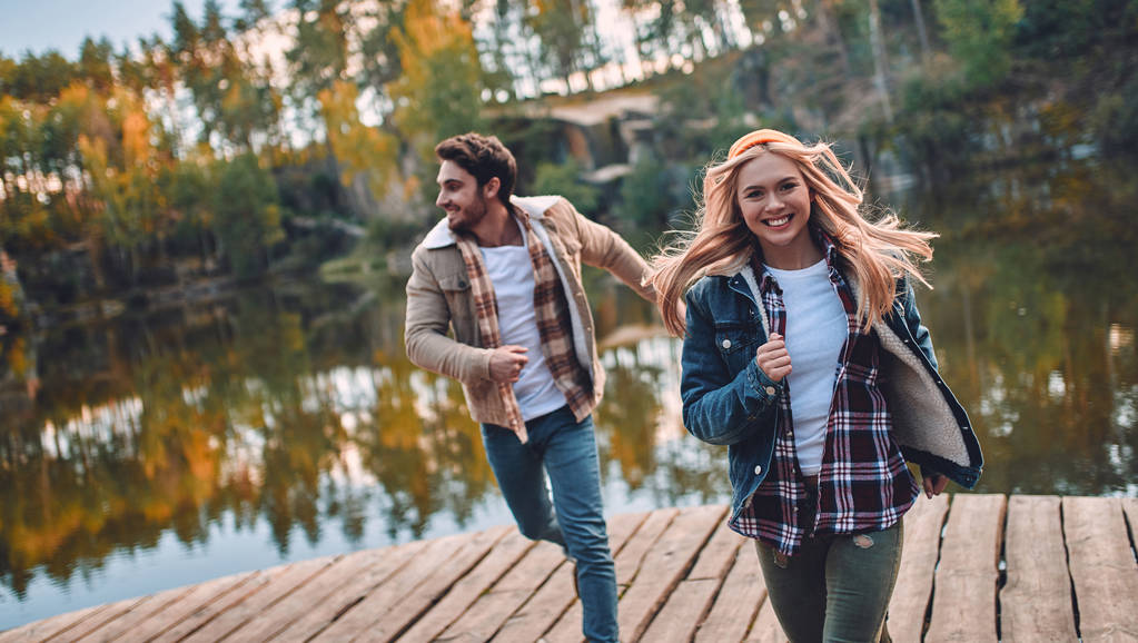 Young couple of tourists are exploring new places. Attractive young woman and handsome bearded man are spending time and having fun together on nature. - Photo, Image