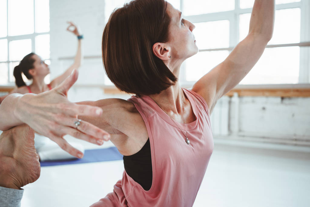 Pratik yoga güçlü yetişkin kadın sağlık korumak için poz veriyor. Grup aktif kadın fithess germe yapmak birlikte kapalı sınıf uygular. Arka plan bulanık - Fotoğraf, Görsel