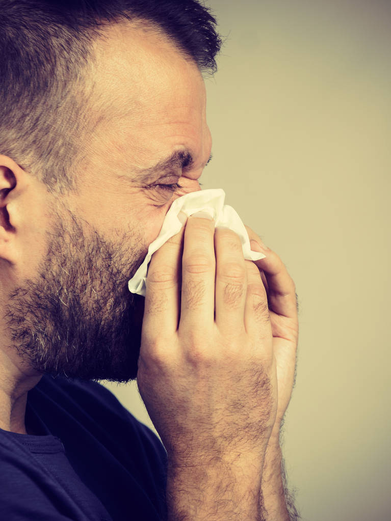 Hombre con gripe, estornudando en tejido higiénico. Tipo enfermo, alérgico a sonarse la nariz. - Foto, Imagen