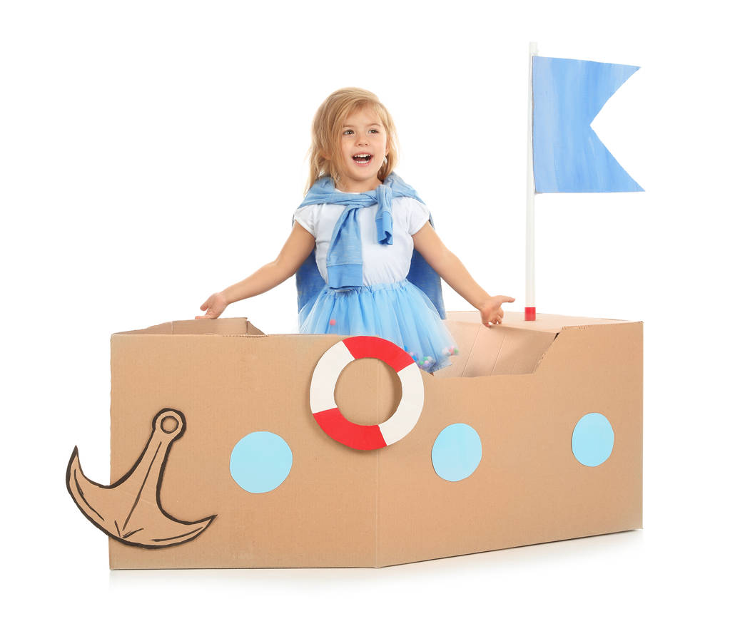 白い背景の上の段ボールの船で遊ぶかわいい女の子 - 写真・画像