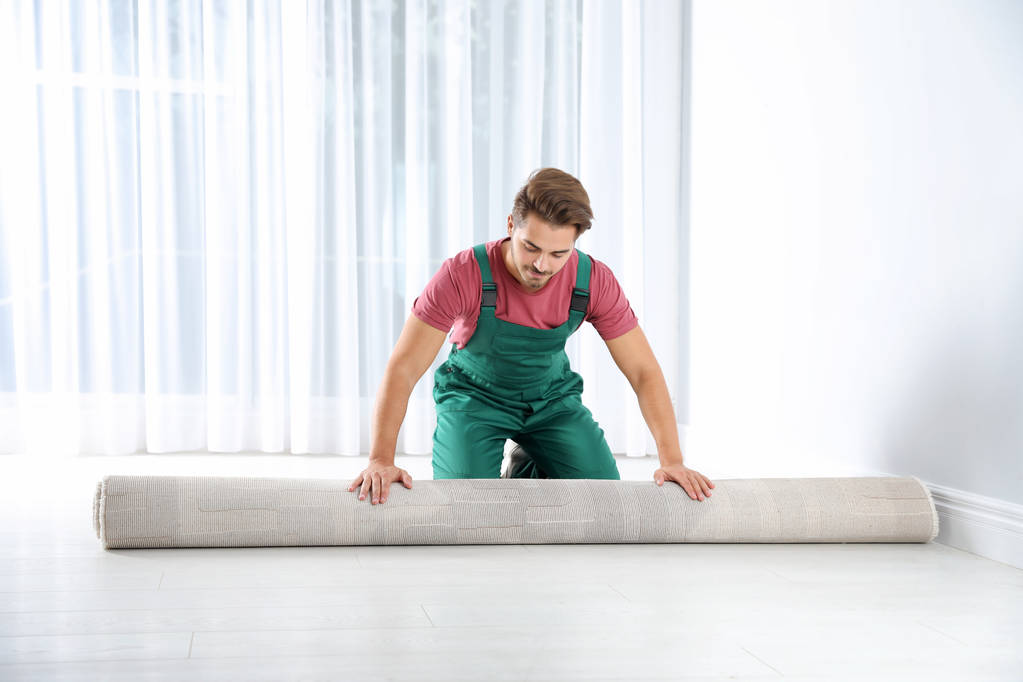 Mann rollt neuen Teppichboden im Haus aus - Foto, Bild
