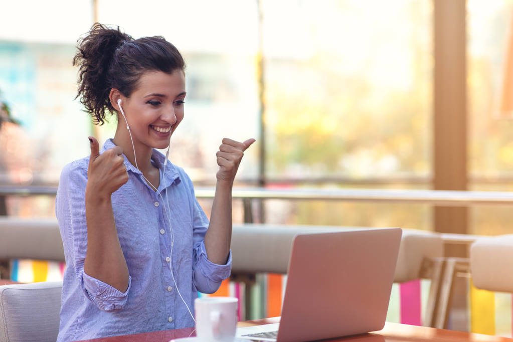 jovem atraente menina de raça mista que está sorrindo olhando para sua tela do laptop durante a chamada de vídeo
 - Foto, Imagem